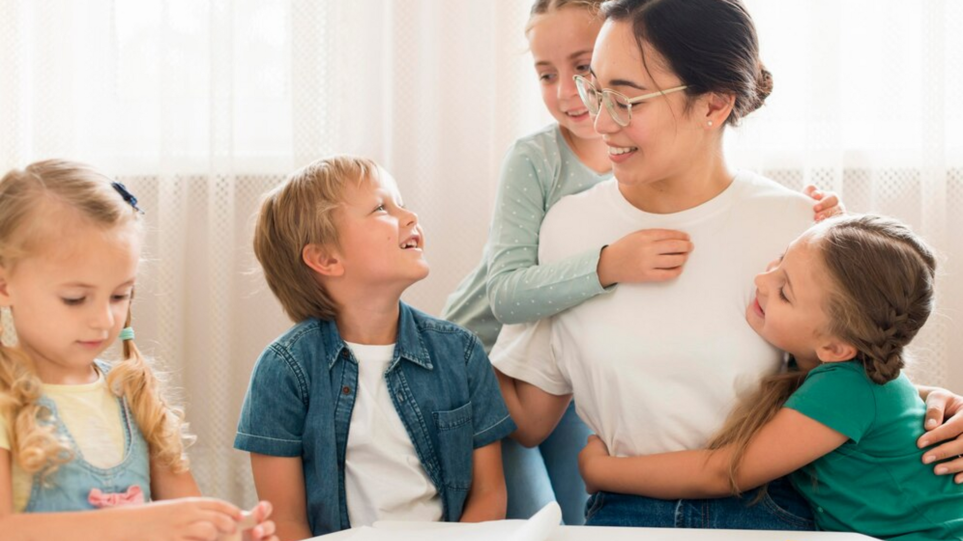 A woman is sitting at a table with a group of children.
