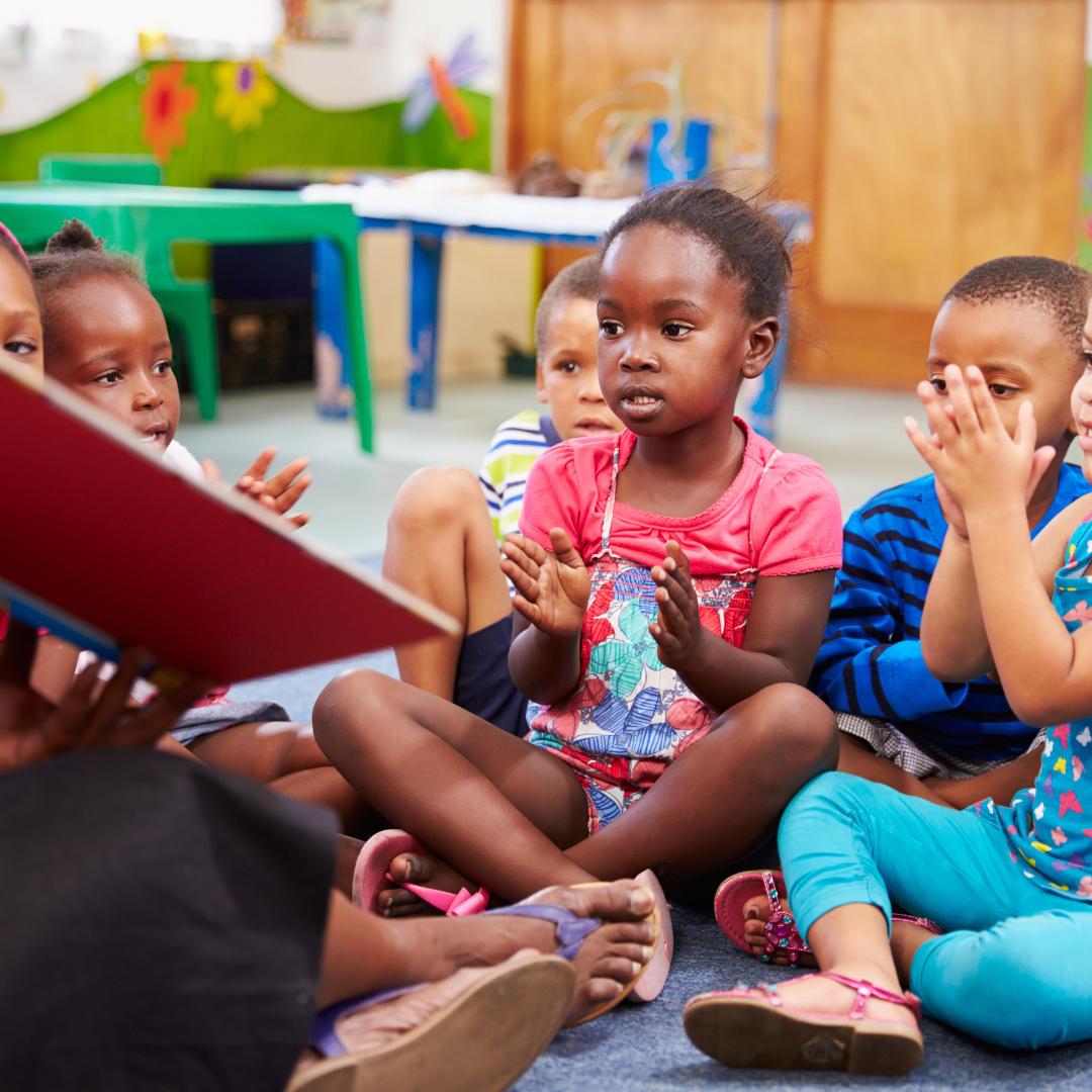 A group of children are sitting on the floor reading a book