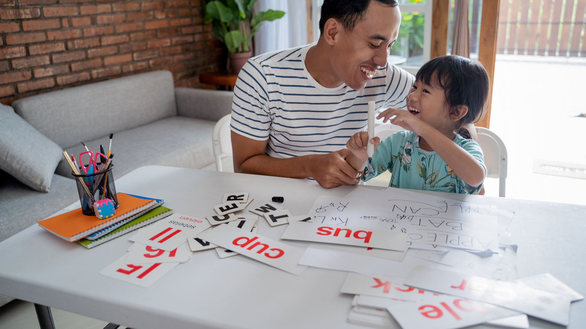 A man and a little girl are sitting at a table playing with cards.