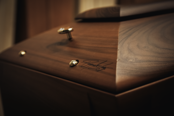 Primo piano di una bara di legno scuro e lucido con finiture decorative.