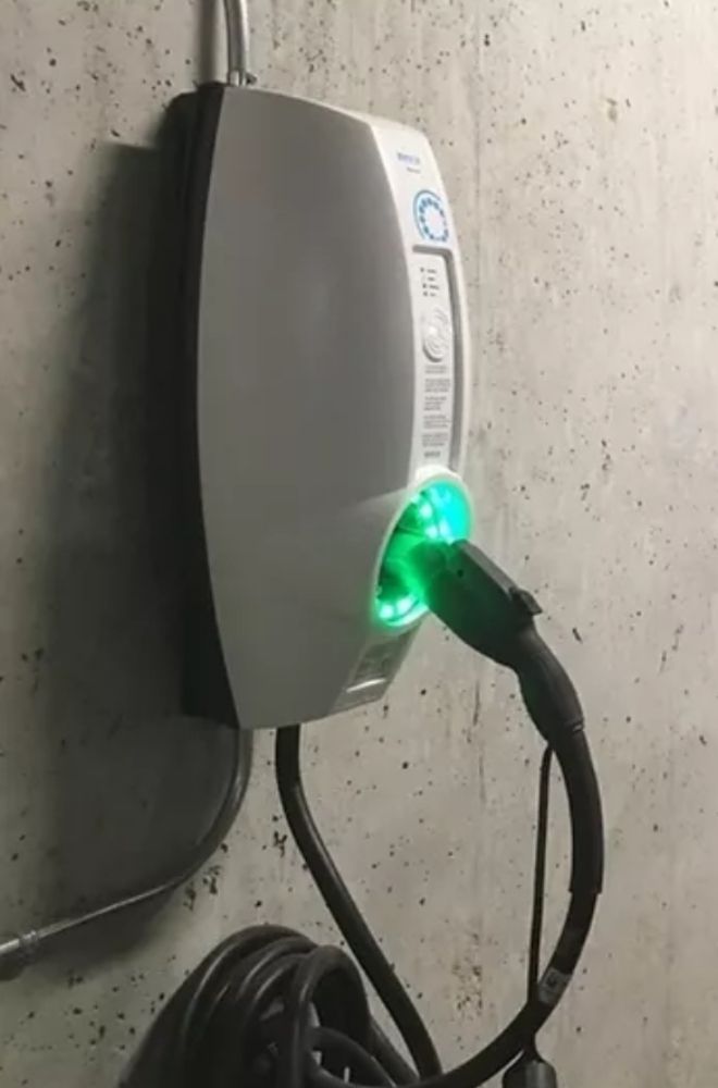 A charger is plugged into a wall and has a green light on it.