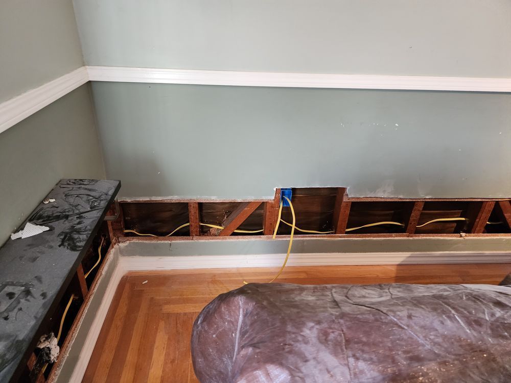 A room with a hole in the wall and a wooden floor.