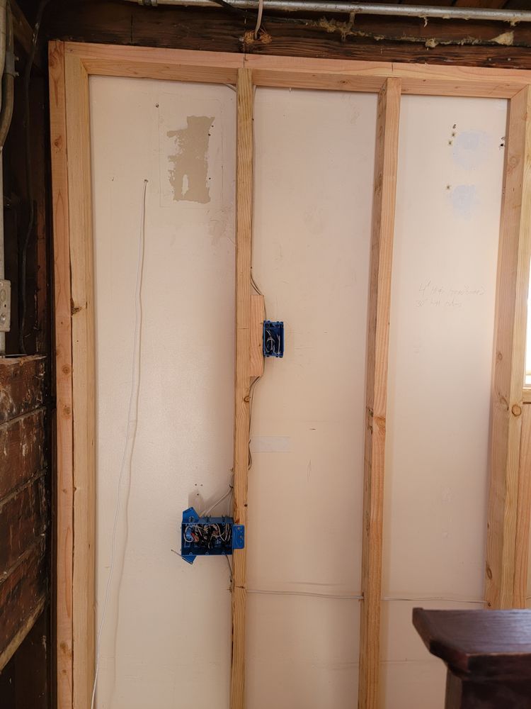 A wooden frame is being built around a white wall in a room.