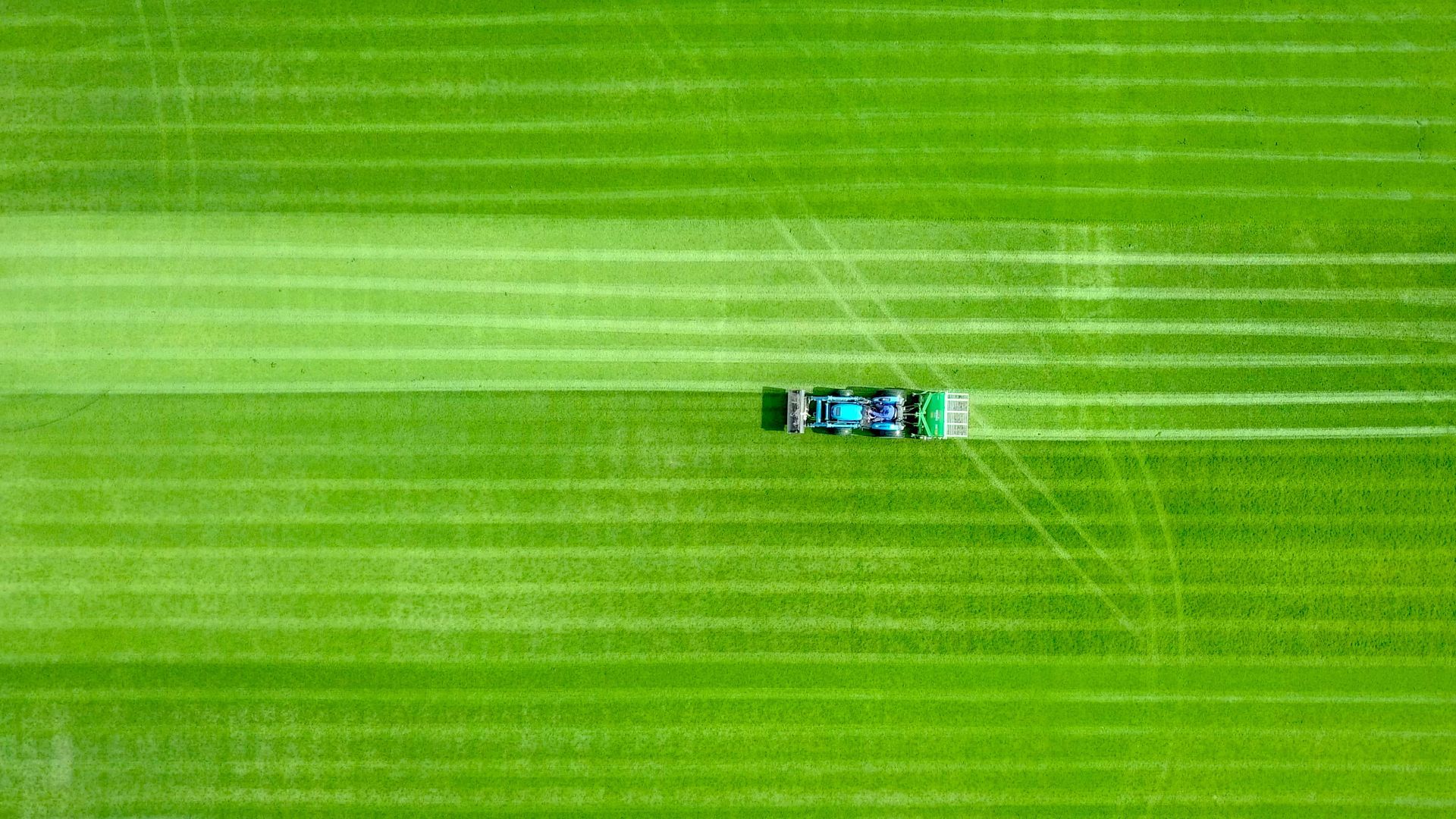 An aerial view of a lawn mower cutting a lush green field.
