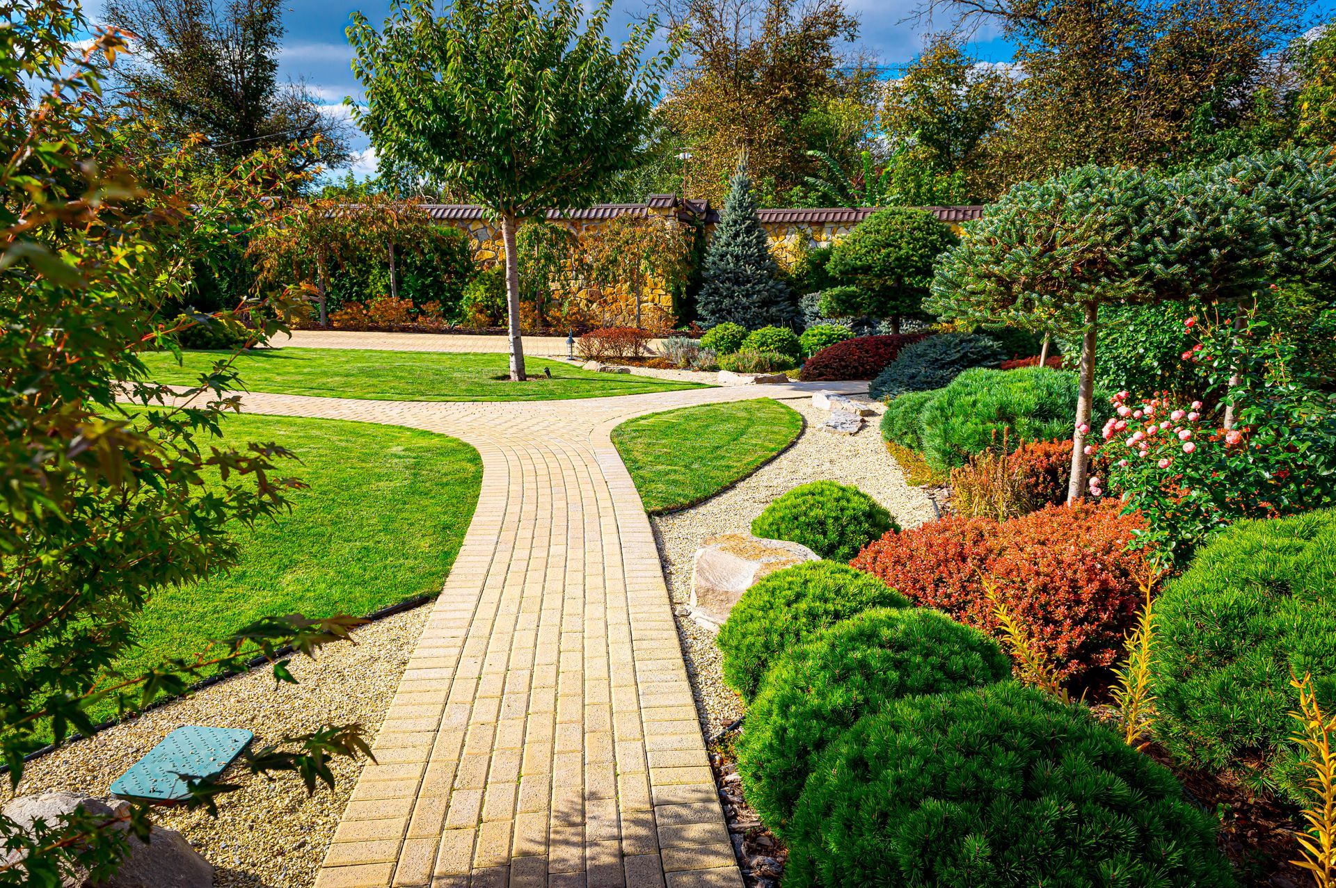 A brick walkway in a park surrounded by trees and bushes.