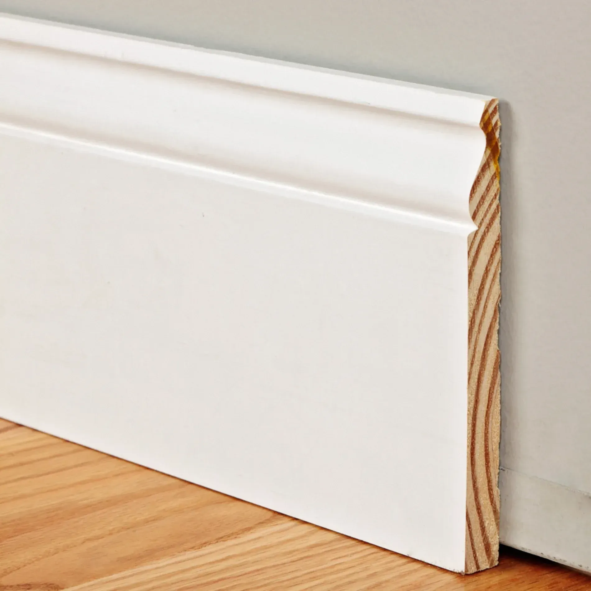 A white skirting board is sitting on a wooden floor