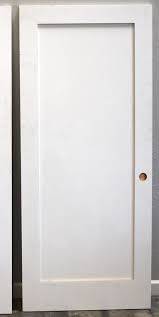 A white door is sitting on a wooden floor next to a wall.