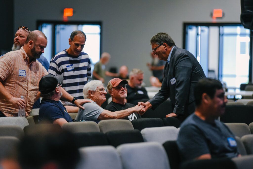 Men in the sanctuary greet each other, shaking hands.