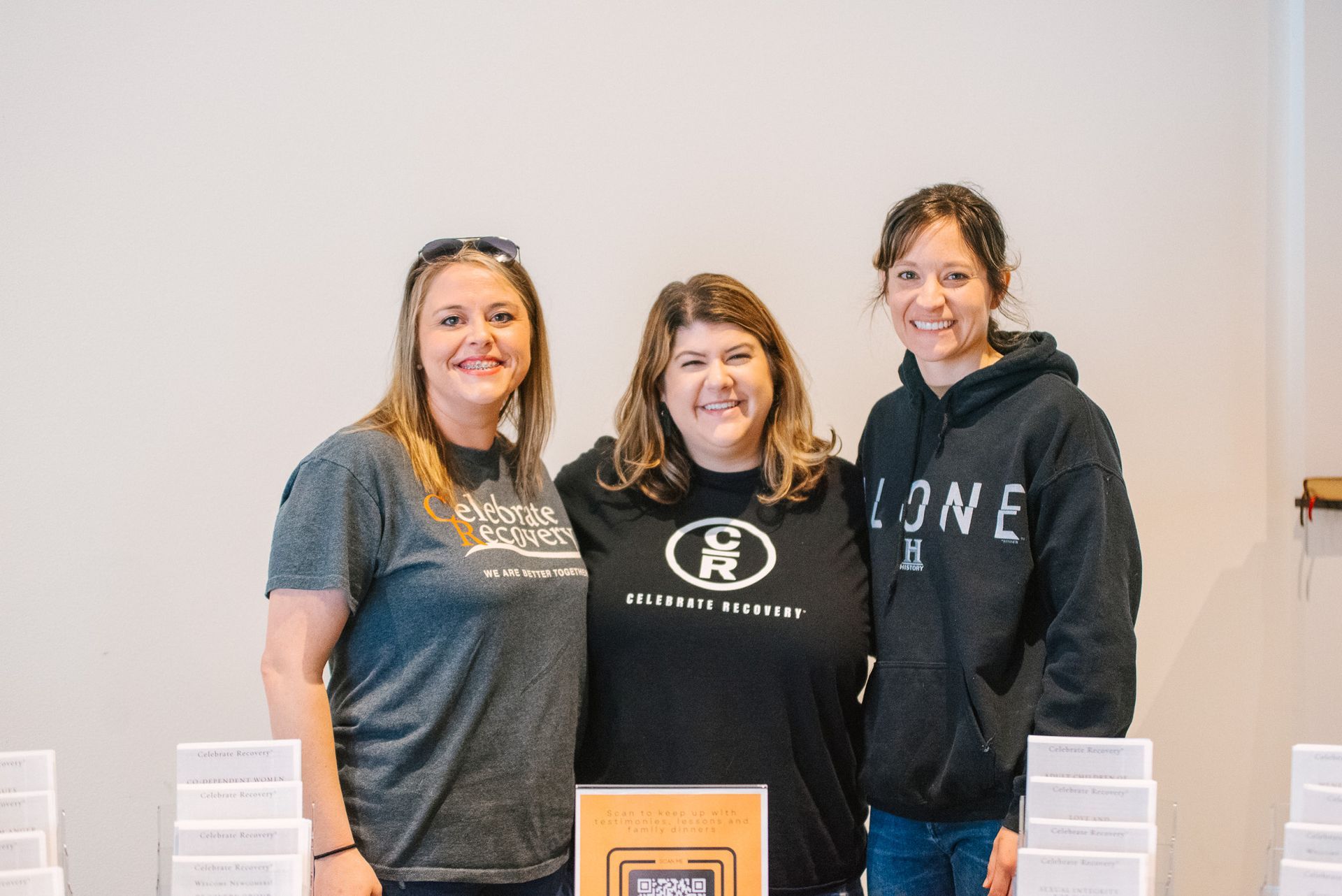 Three women smiling at a Celebrate recovery Table.