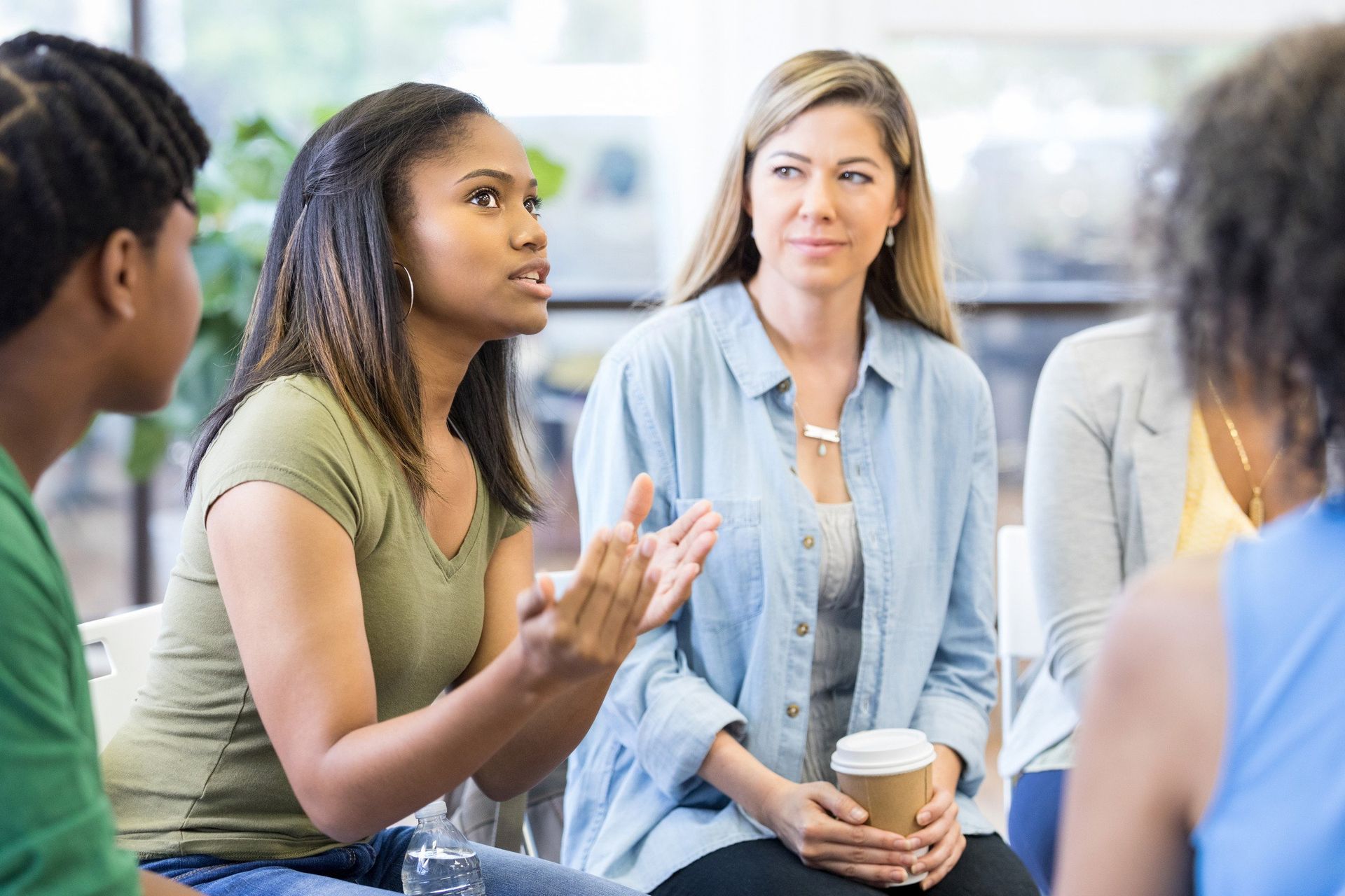 A group of women are sitting in a circle talking to each other.