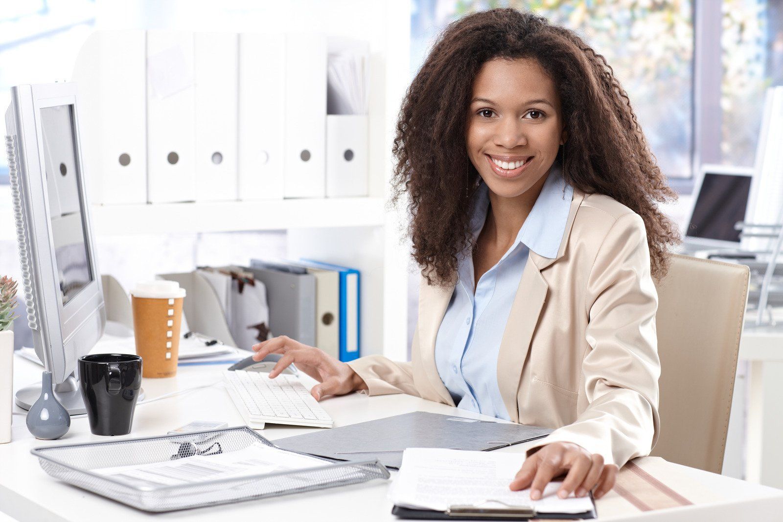 A woman is sitting at a desk in front of a computer.