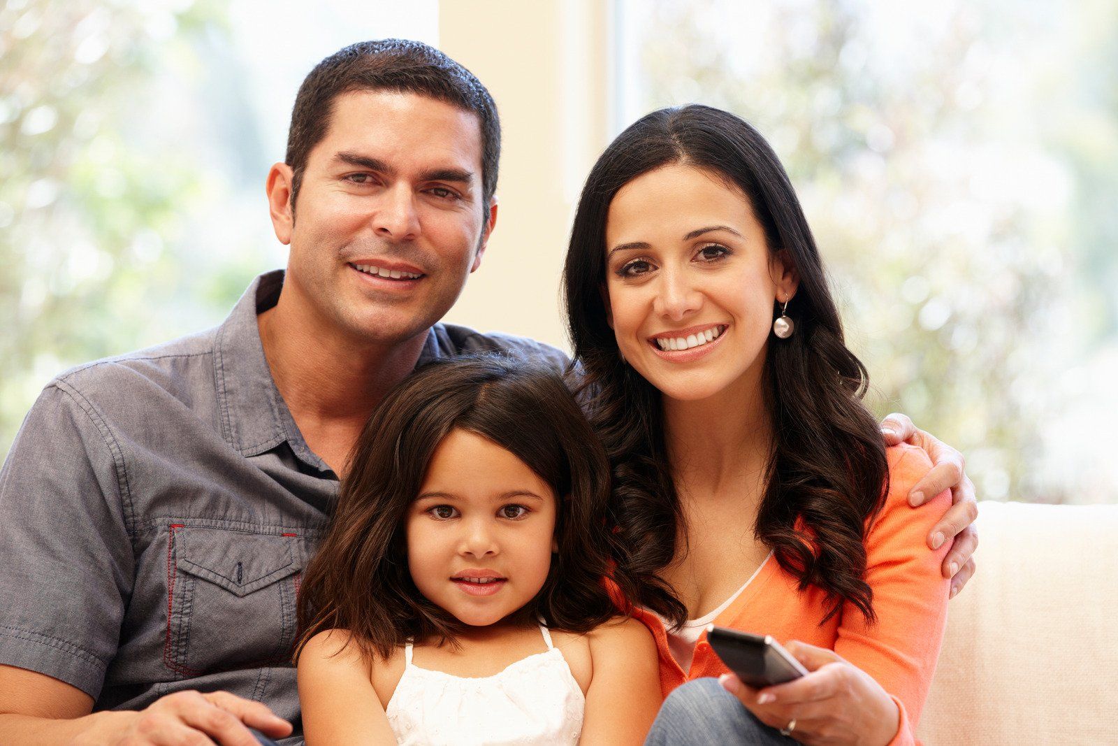 A family is posing for a picture while sitting on a couch.