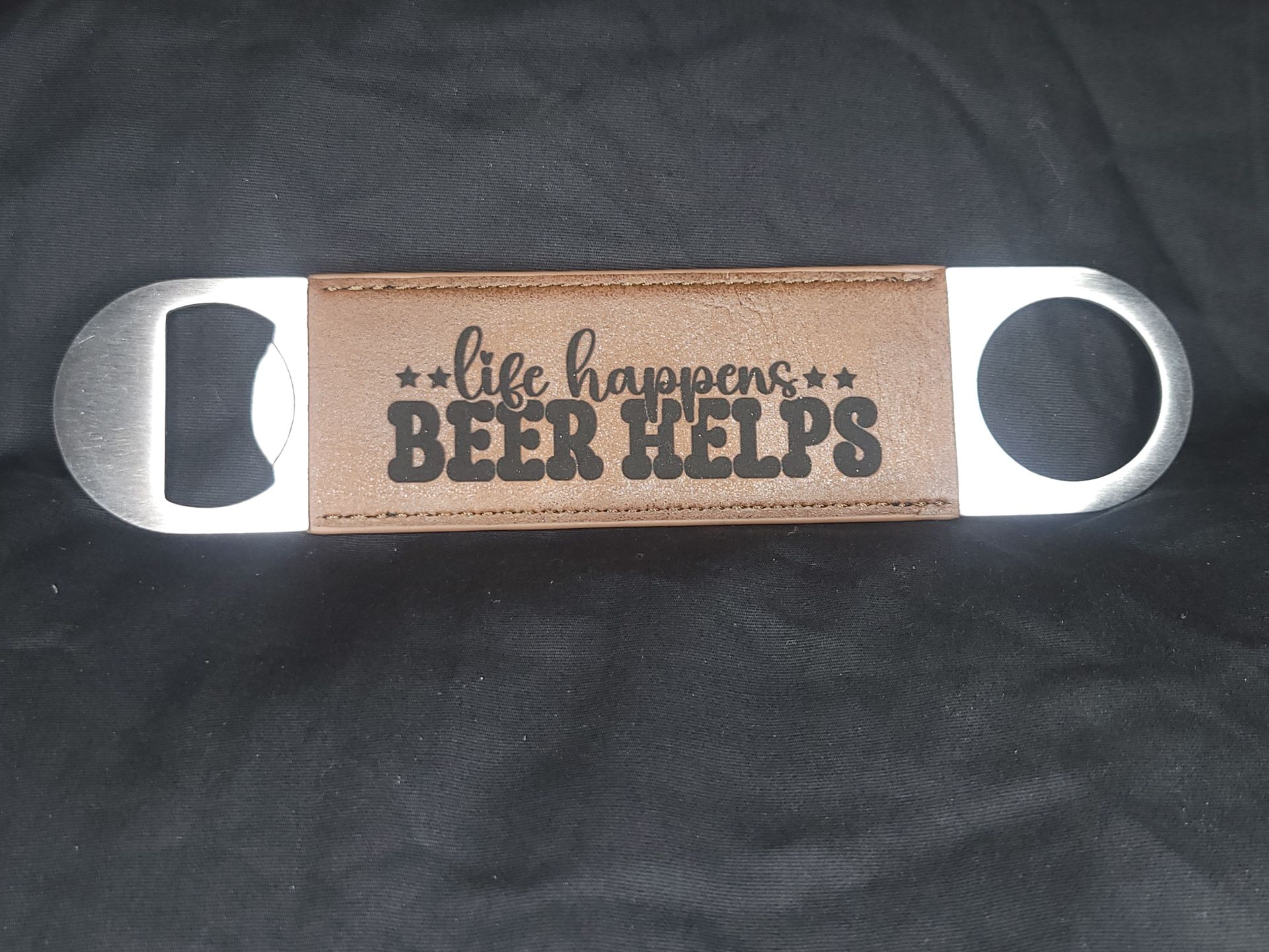 A bottle opener with the words `` life happens beer helps '' on it