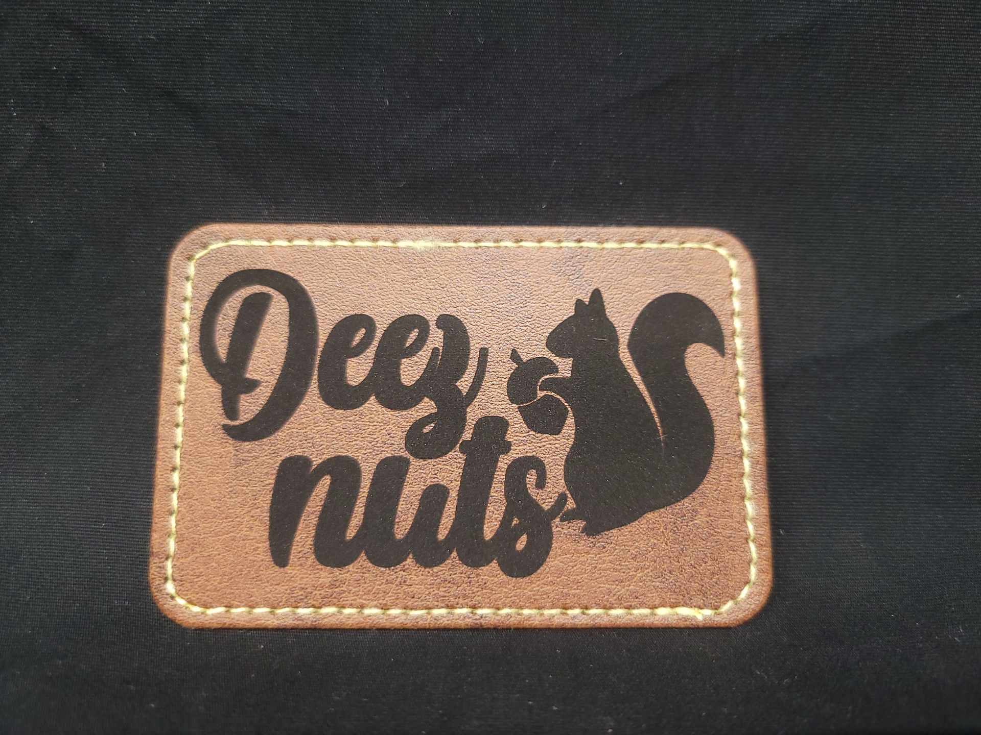 A brown leather patch with a squirrel and the words deeply nuts