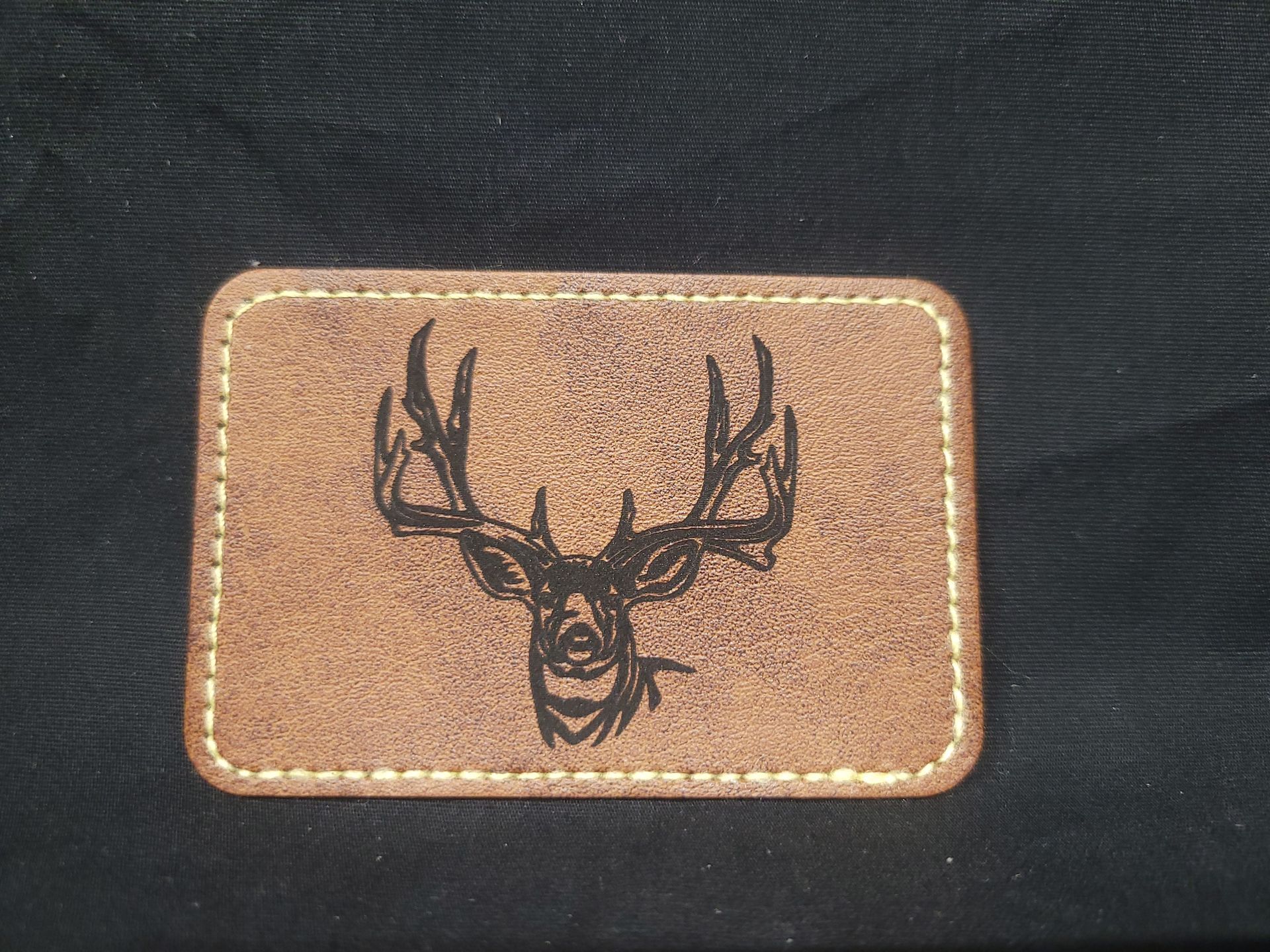 A brown leather patch with a deer head on it