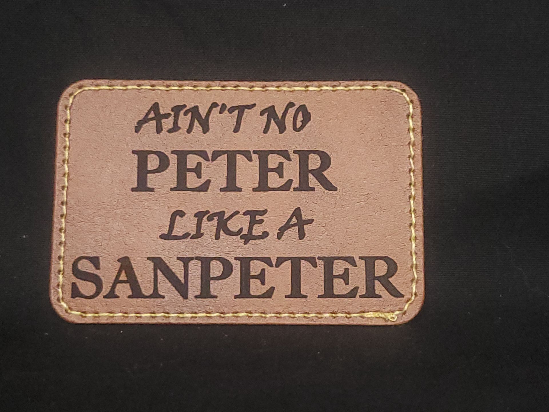 A brown leather patch that says ain t no peter like a sanpeter