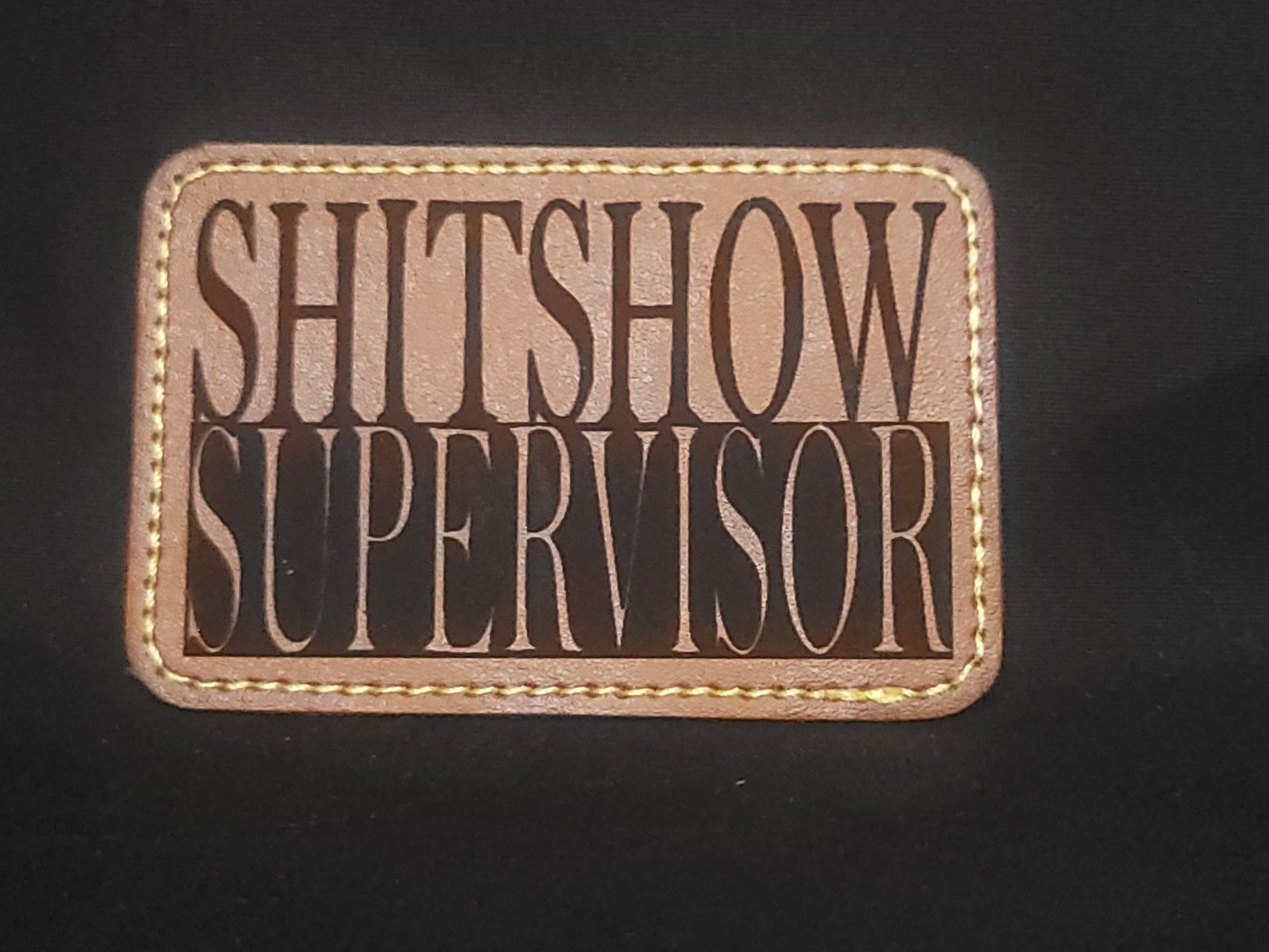 A brown leather patch that says shitshow supervisor