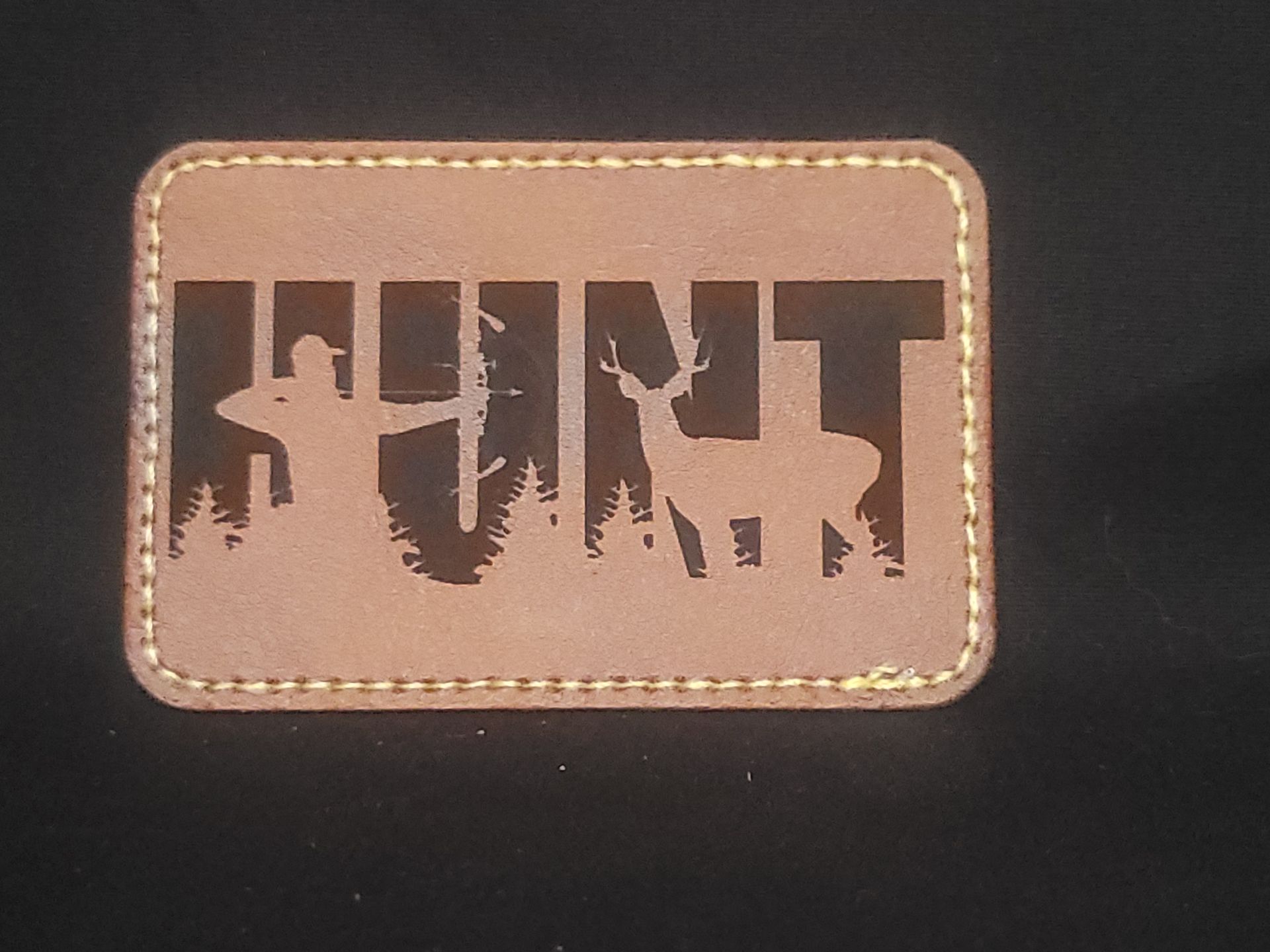 A brown leather patch with the word hunt on it