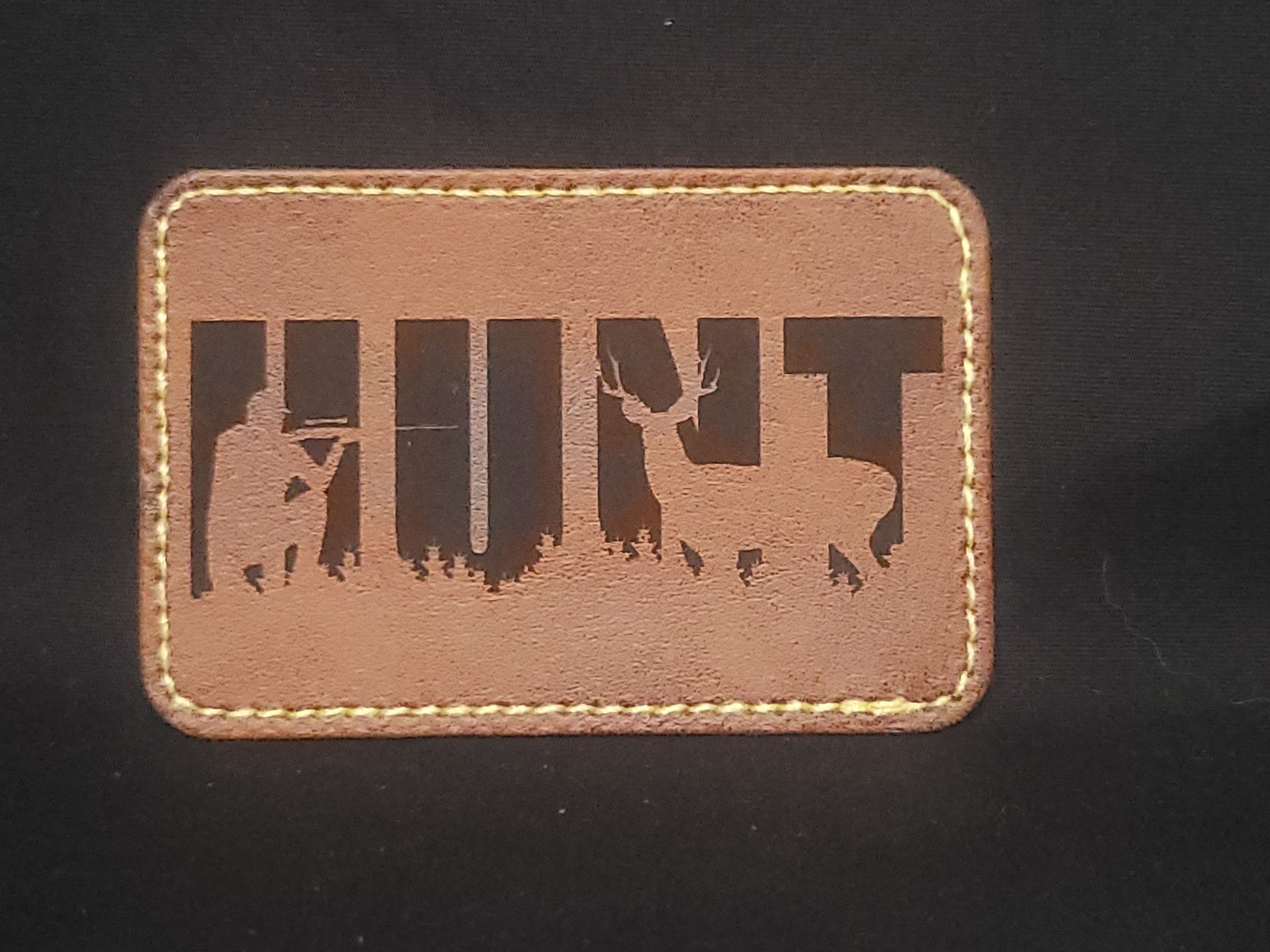 A brown leather patch with the word hunt on it