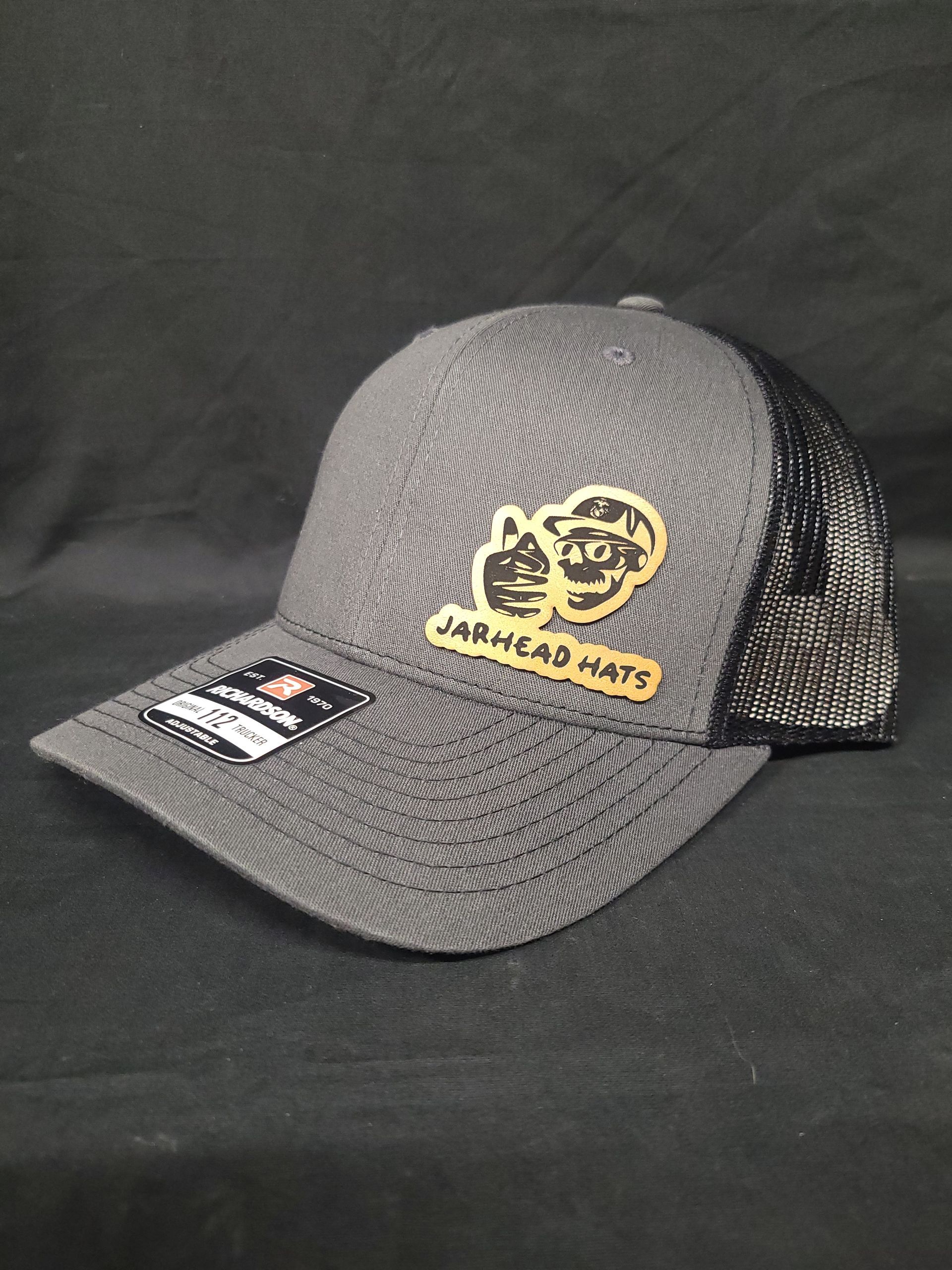 A gray baseball cap with a yellow logo on it is sitting on a black table.