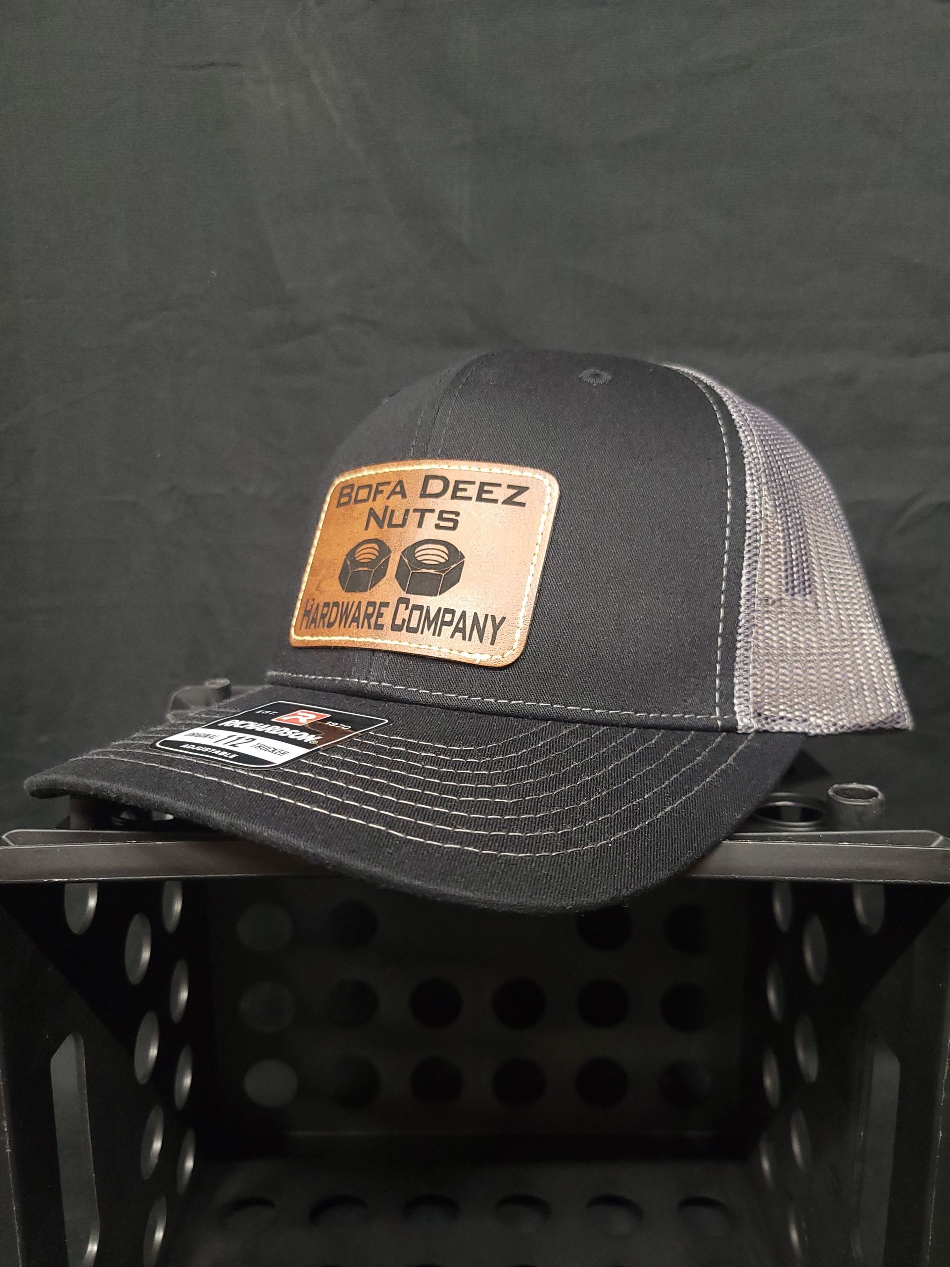 A black and gray hat with a leather patch on it is sitting on top of a metal crate.