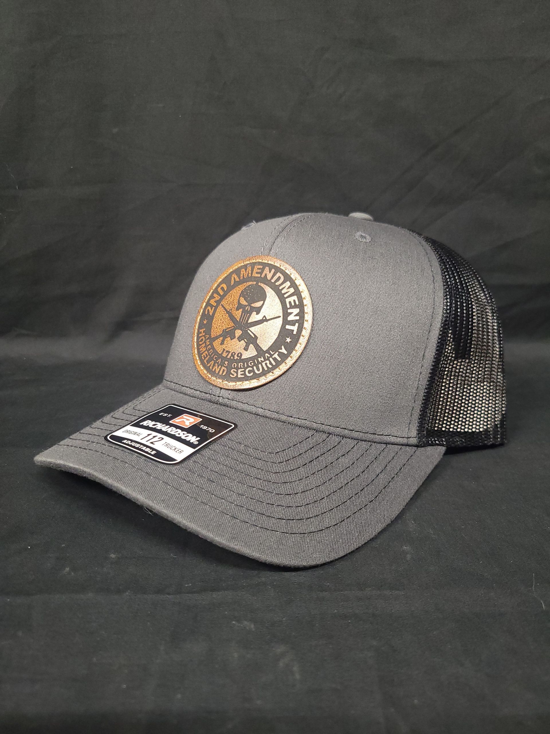 A gray baseball cap with a gold logo on it is sitting on a black table.