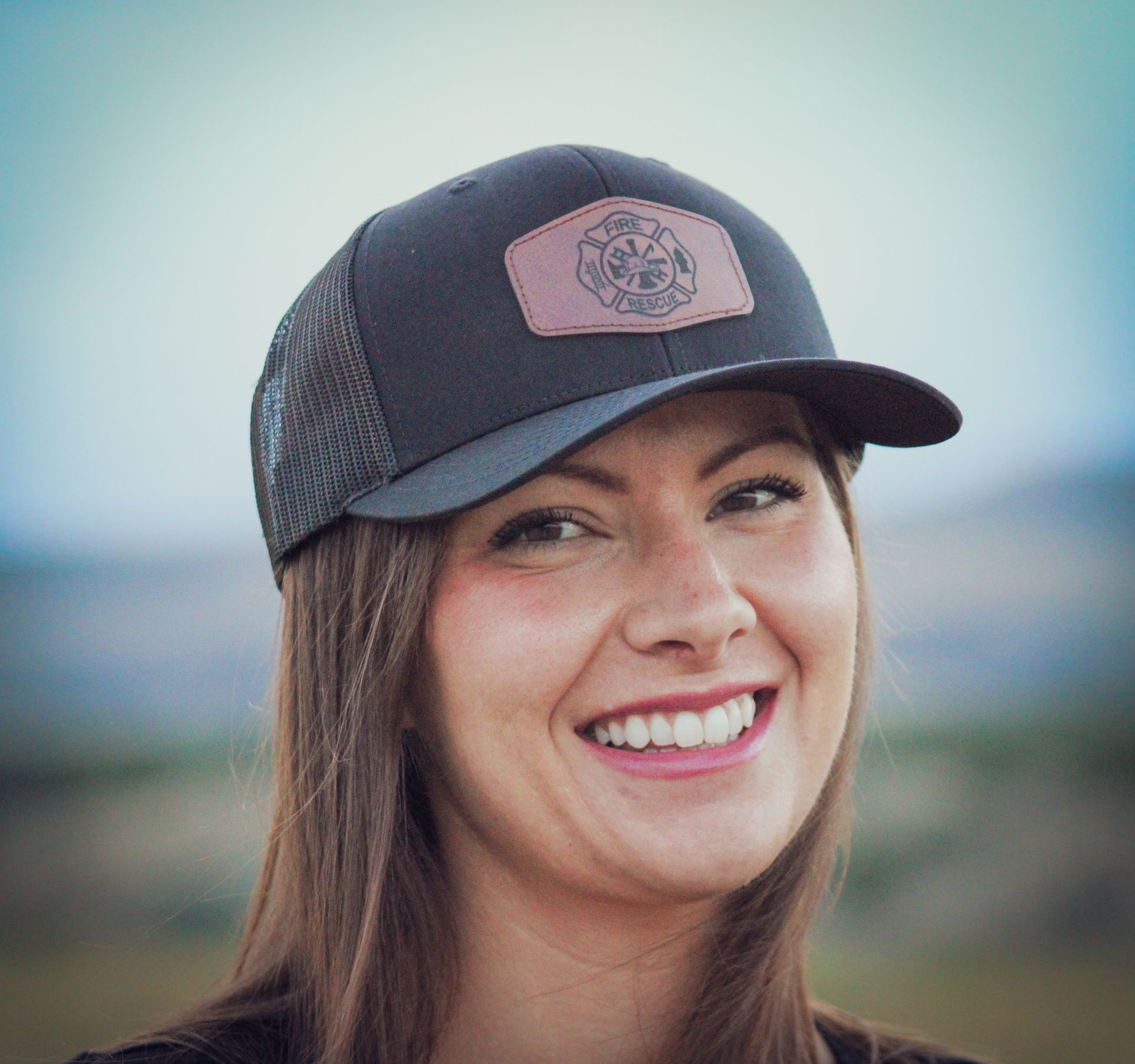 A woman wearing a hat is smiling and looking at the camera.