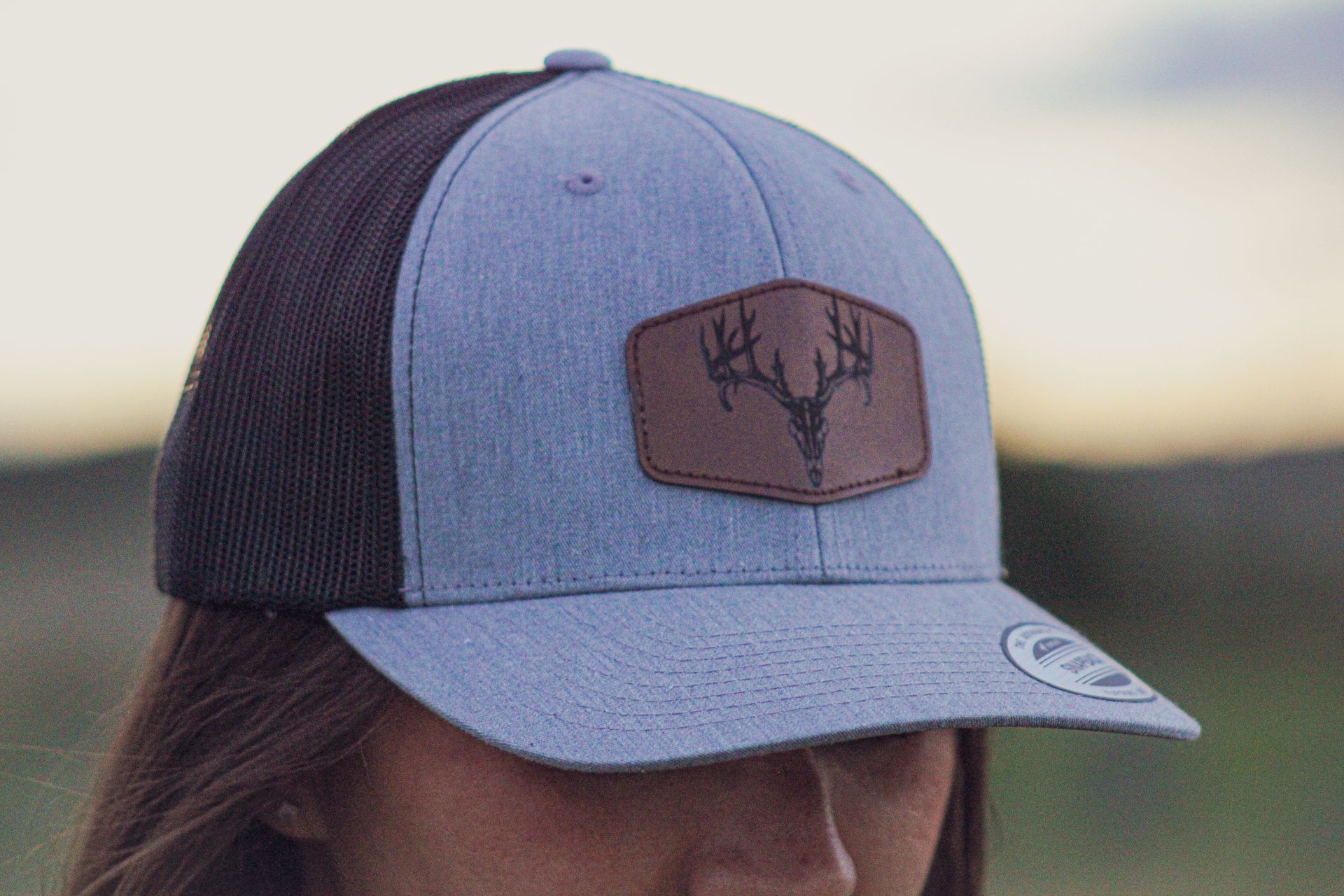 A woman is wearing a hat with a deer on it.