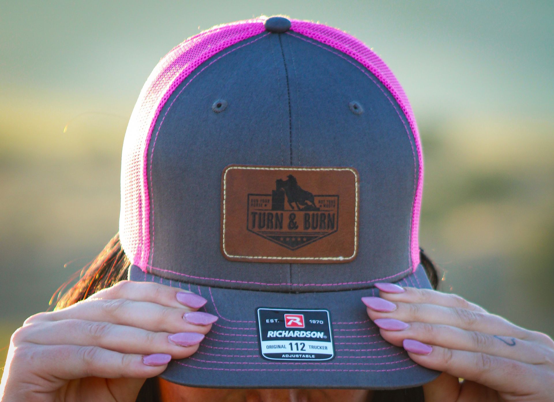 A woman is wearing a hat with a leather patch on it.