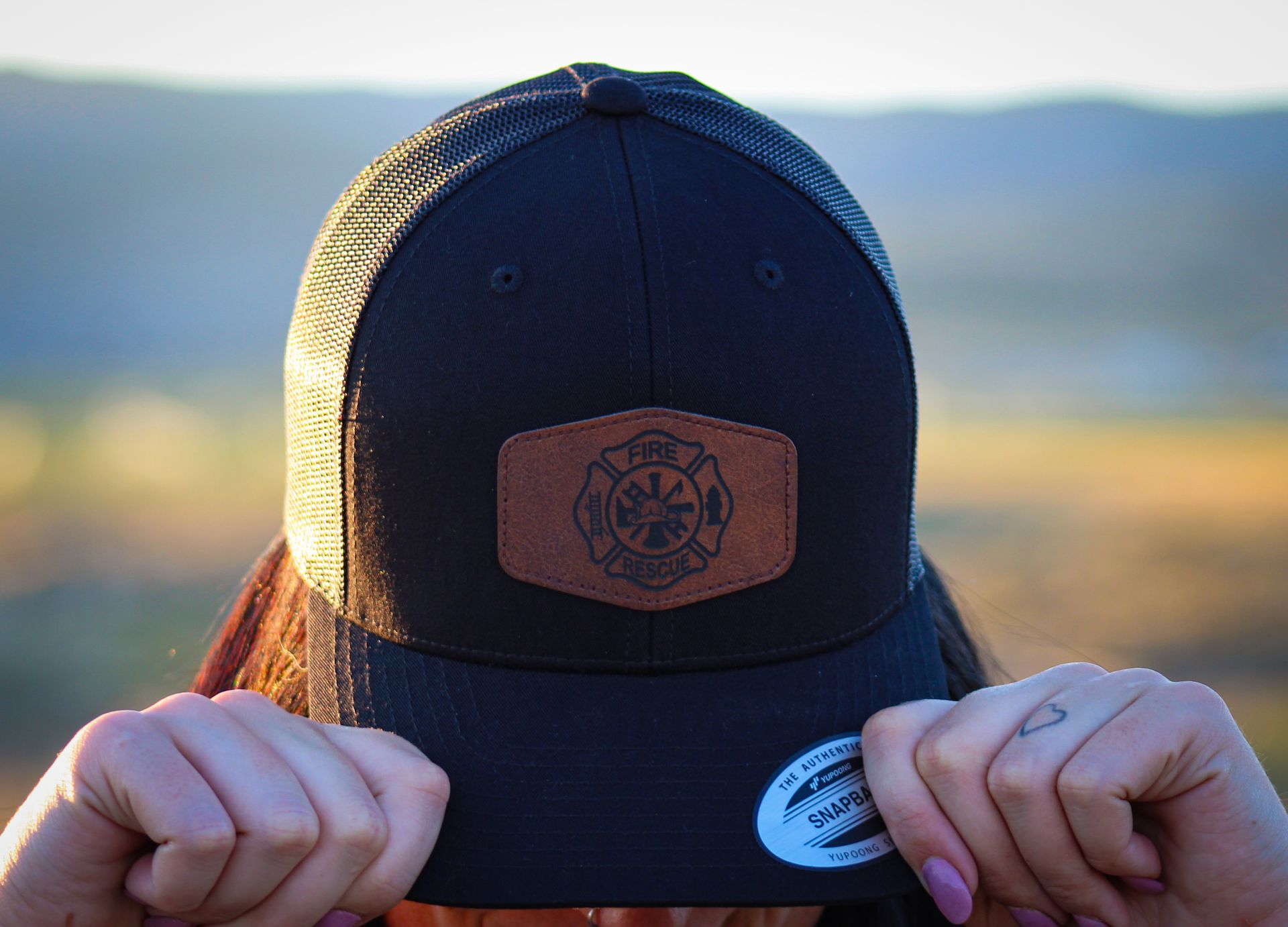 A woman is holding a black hat in front of her face.