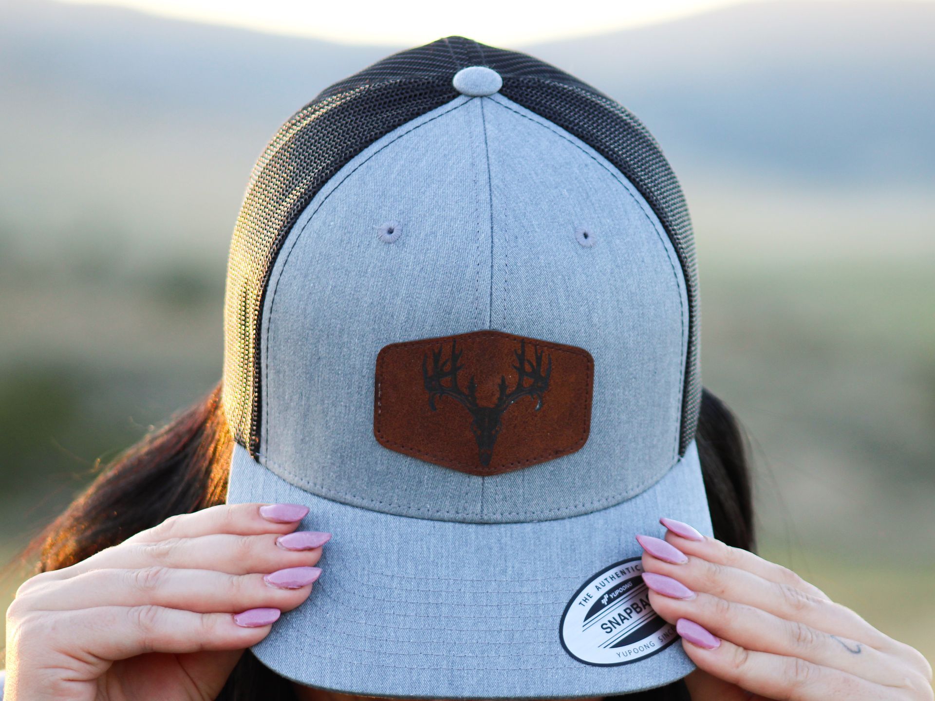 A woman is holding a hat in front of her face.