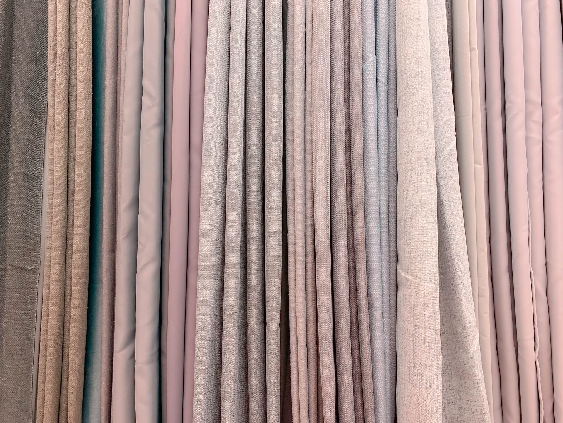 Un mucchio di tende di diversi colori sono appese a una parete.