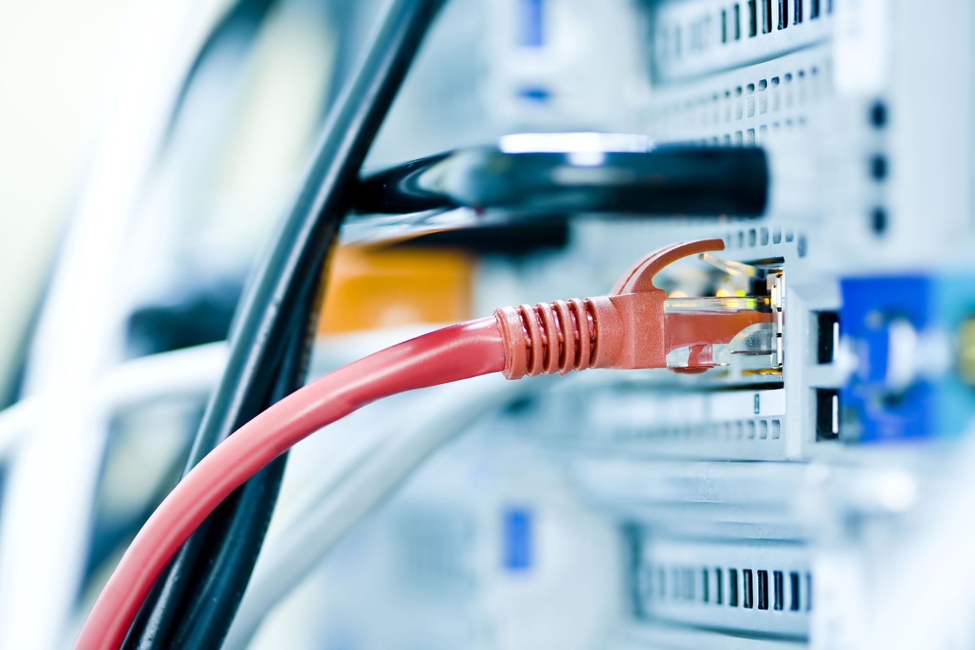 A red ethernet cable is plugged into a server.