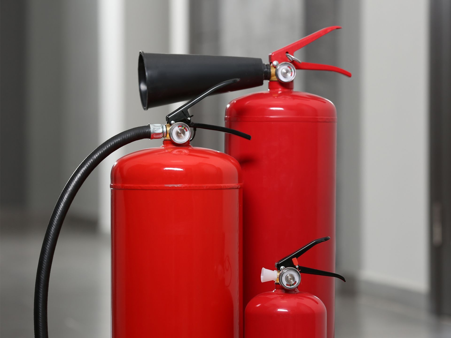Three red fire extinguishers of varying sizes.