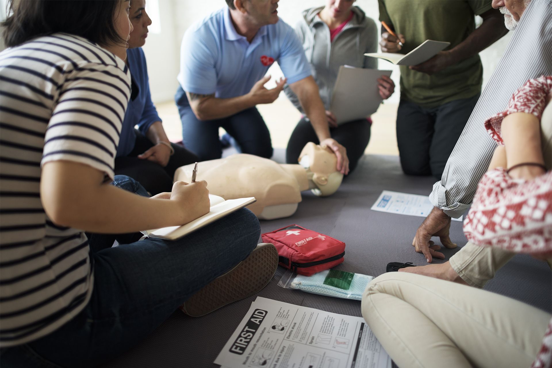 People in a first aid class practice CPR on a mannequin.