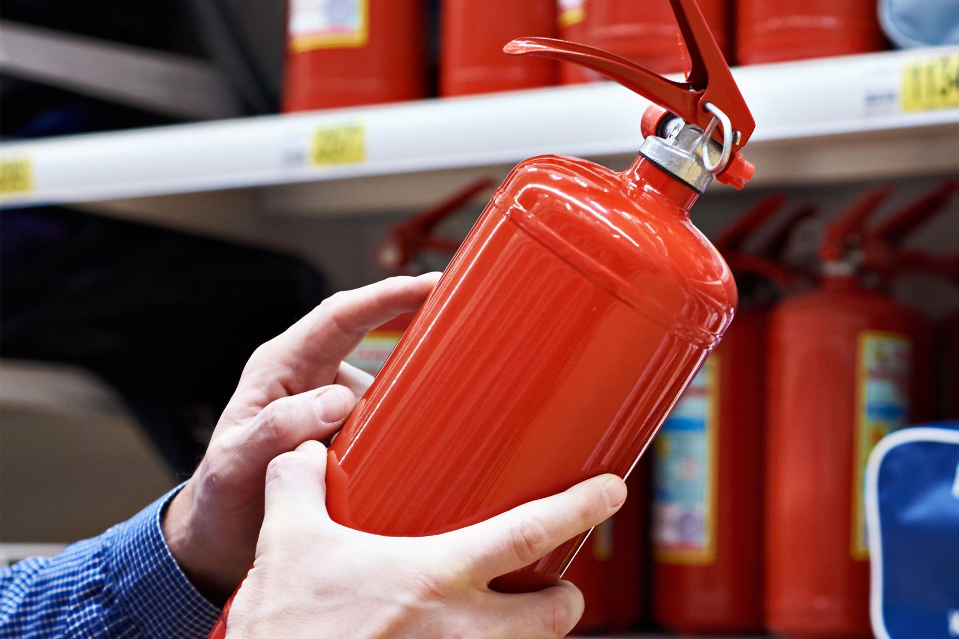 Person holding a red fire extinguisher on a shelf.