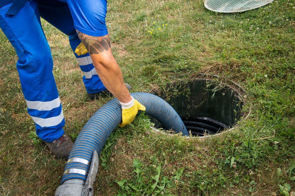 A man is pumping a hose into a septic tank.