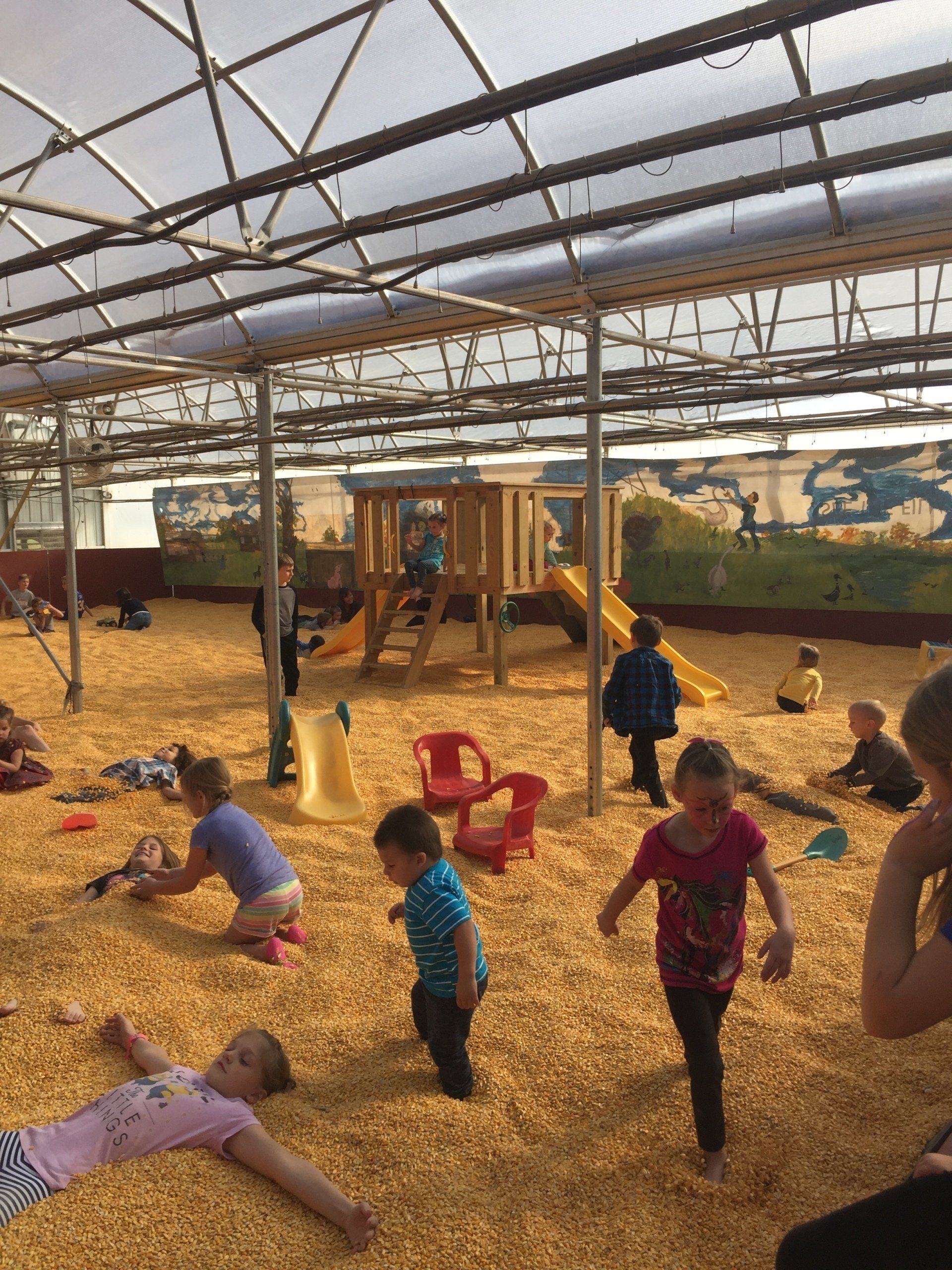 A group of children are playing in a playground filled with wood chips
