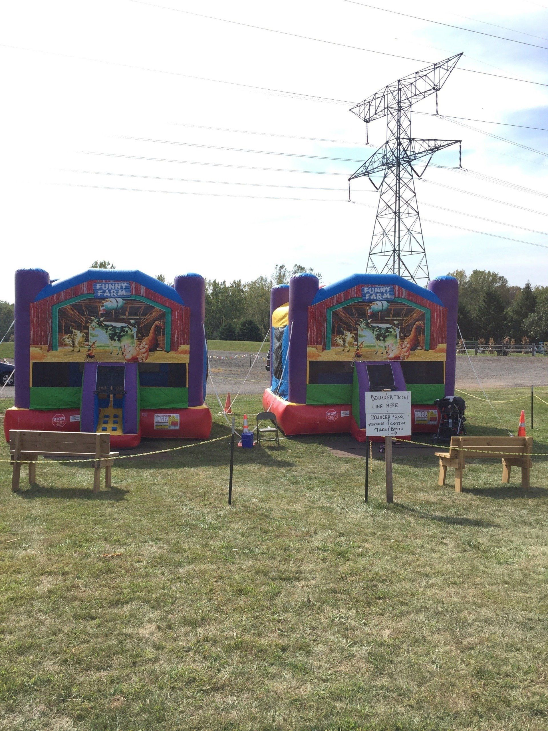 Two bouncy houses in a field with a sign that says no dogs