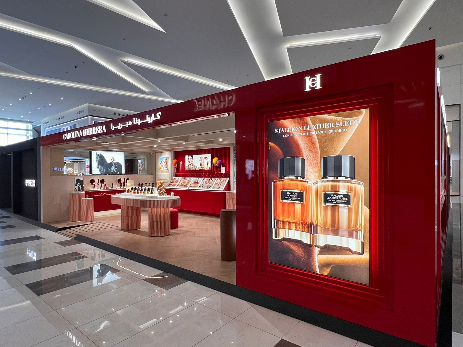 Red Hermes perfume kiosk in a mall. Displays perfume bottles and products.