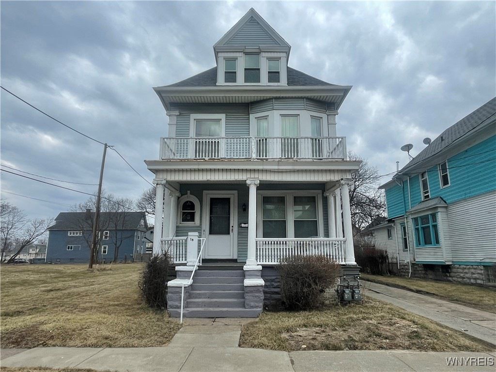 Front view of 18 Girard Pl. A two-story city home with a covered front porch, and a small front yard.