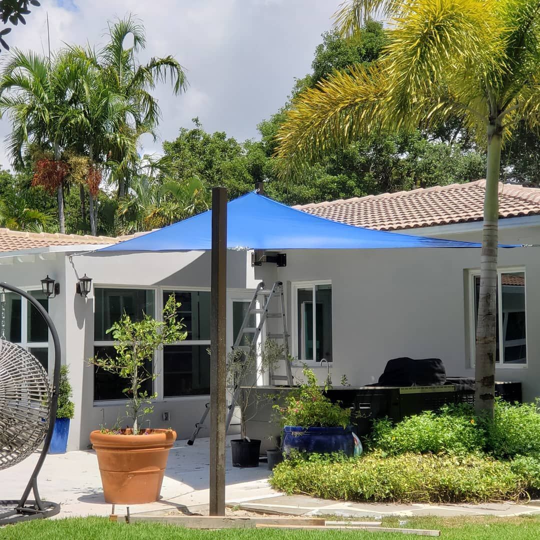 A house with a blue umbrella and a fan in front of it.