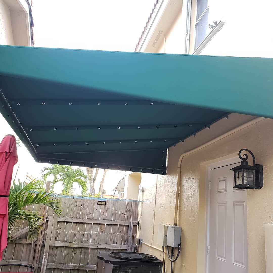 A green awning is sitting on the side of a house.