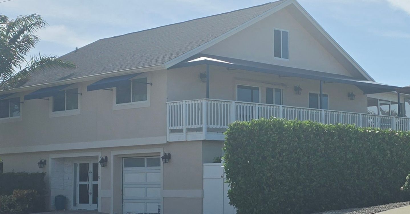 A large house with a balcony and a hedge in front of it.