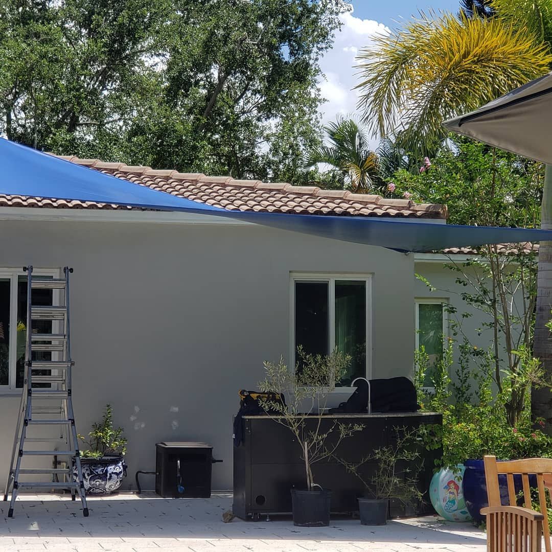 A house with a blue umbrella on the roof and a ladder in front of it.