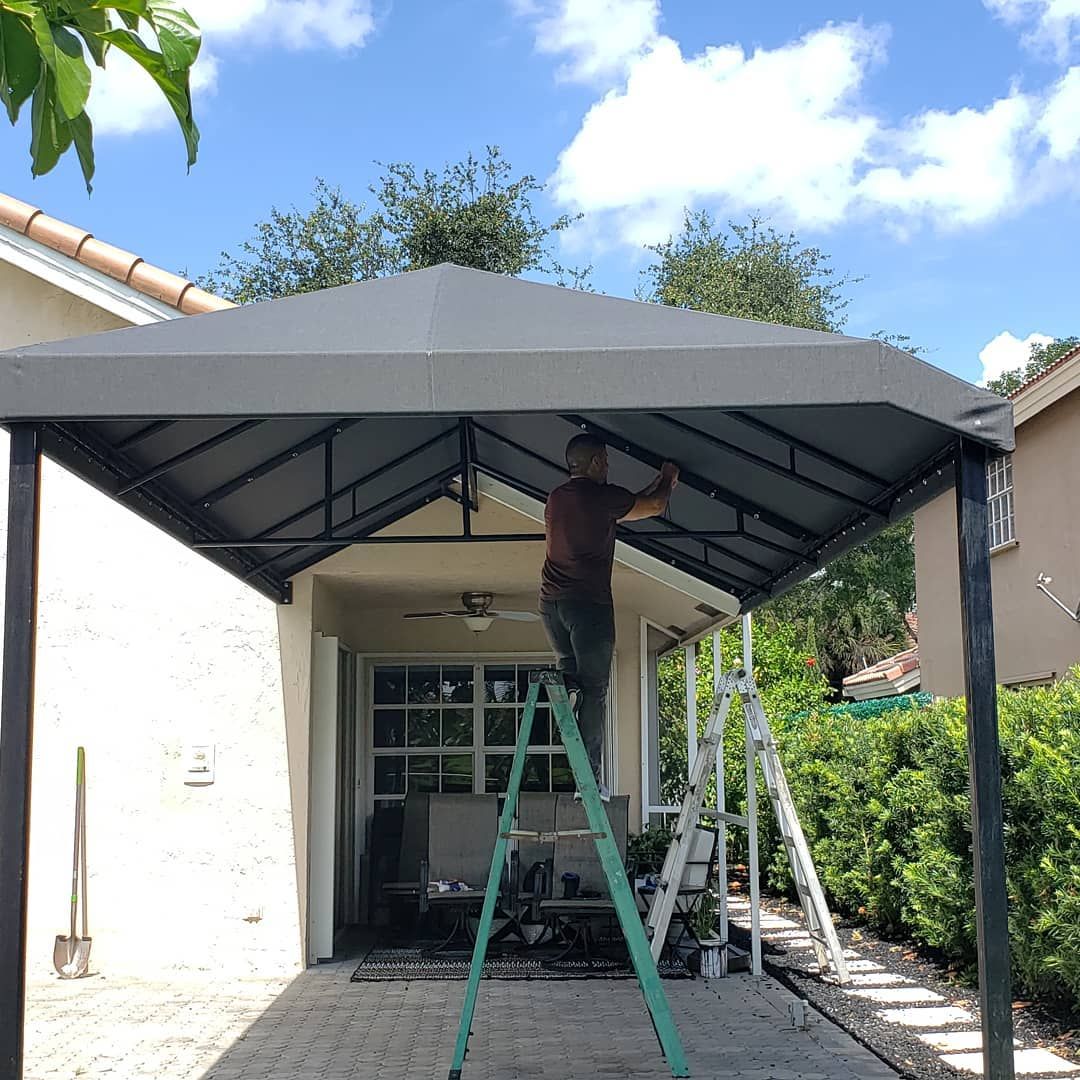 A man is standing on a ladder under a canopy.