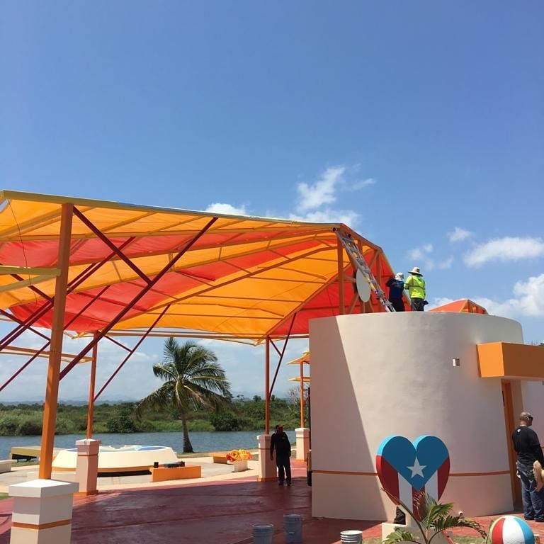A group of people standing under an orange canopy
