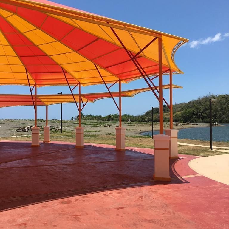 A row of red and yellow umbrellas with a lake in the background