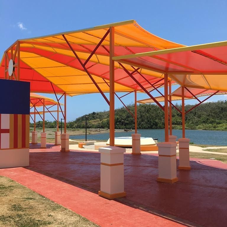 A row of colorful umbrellas are lined up in front of a body of water