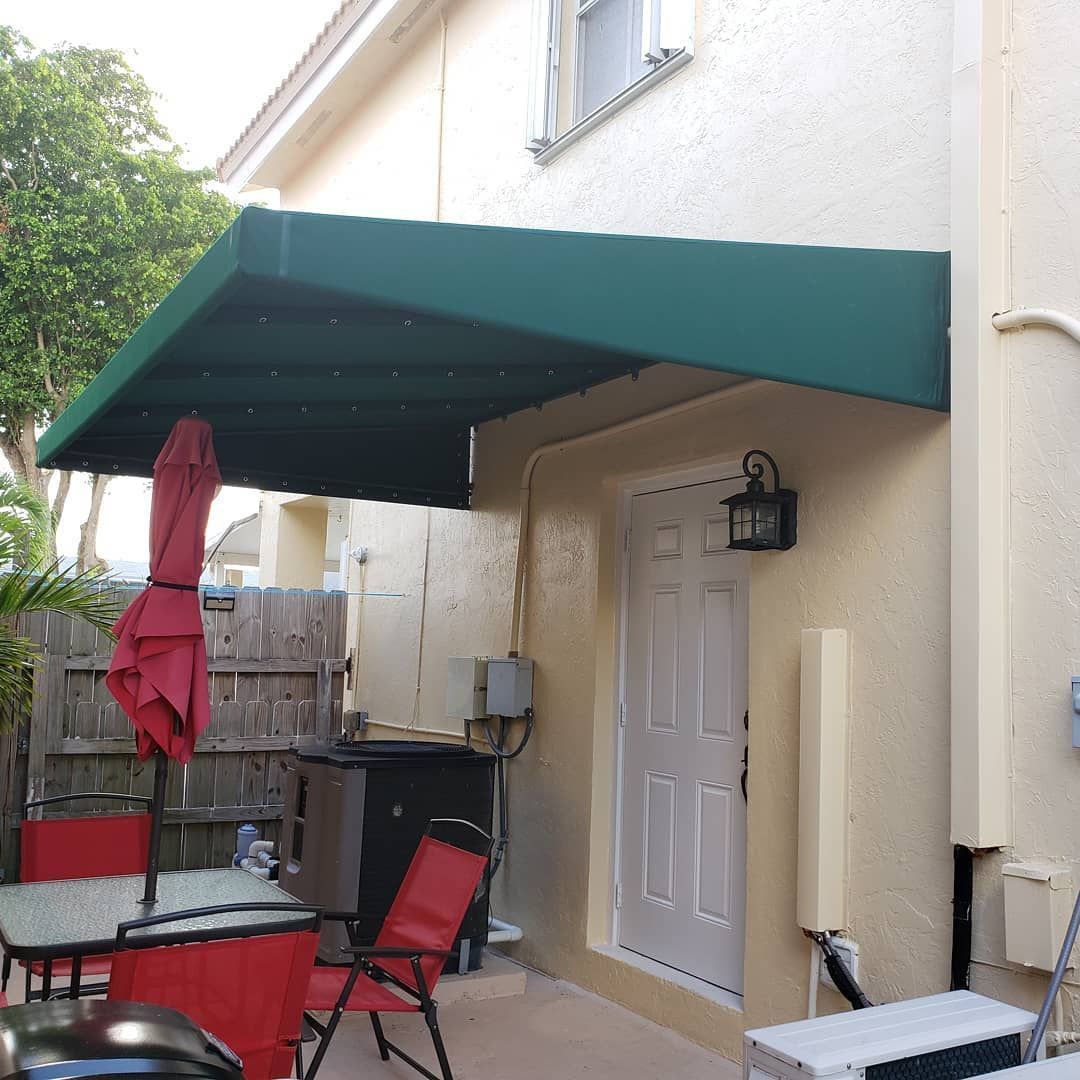 A patio with tables and chairs under a green awning